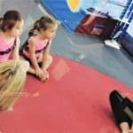twin girls sitting on mat at gymnastics class after-school activities