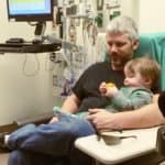 dad holding 1 year old boy waiting to get ear tubes surgery
