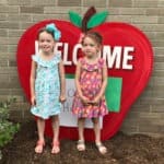twin girls standing by school preparing twins for kindergarten