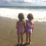 twin 5 year old girls on a beach embrace their individuality