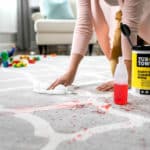 woman cleaning stain on rug after school messes