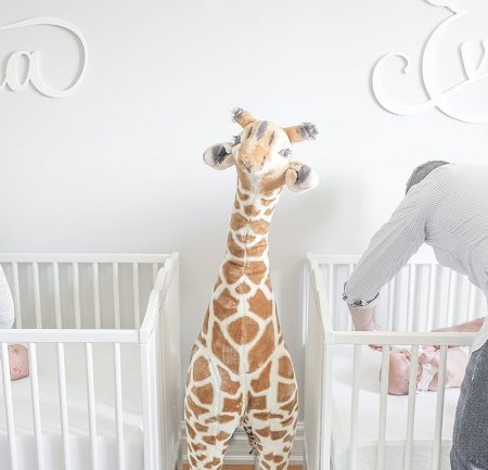 needy twins mom and dad changing diapers in cribs