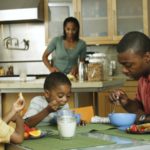 Family in kitchen with twin brothers eating breakfast