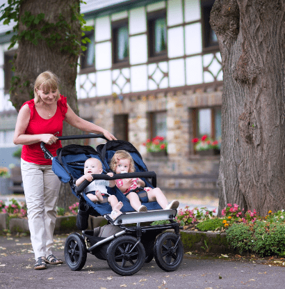 a woman pushing 2 kids in a stroller outside