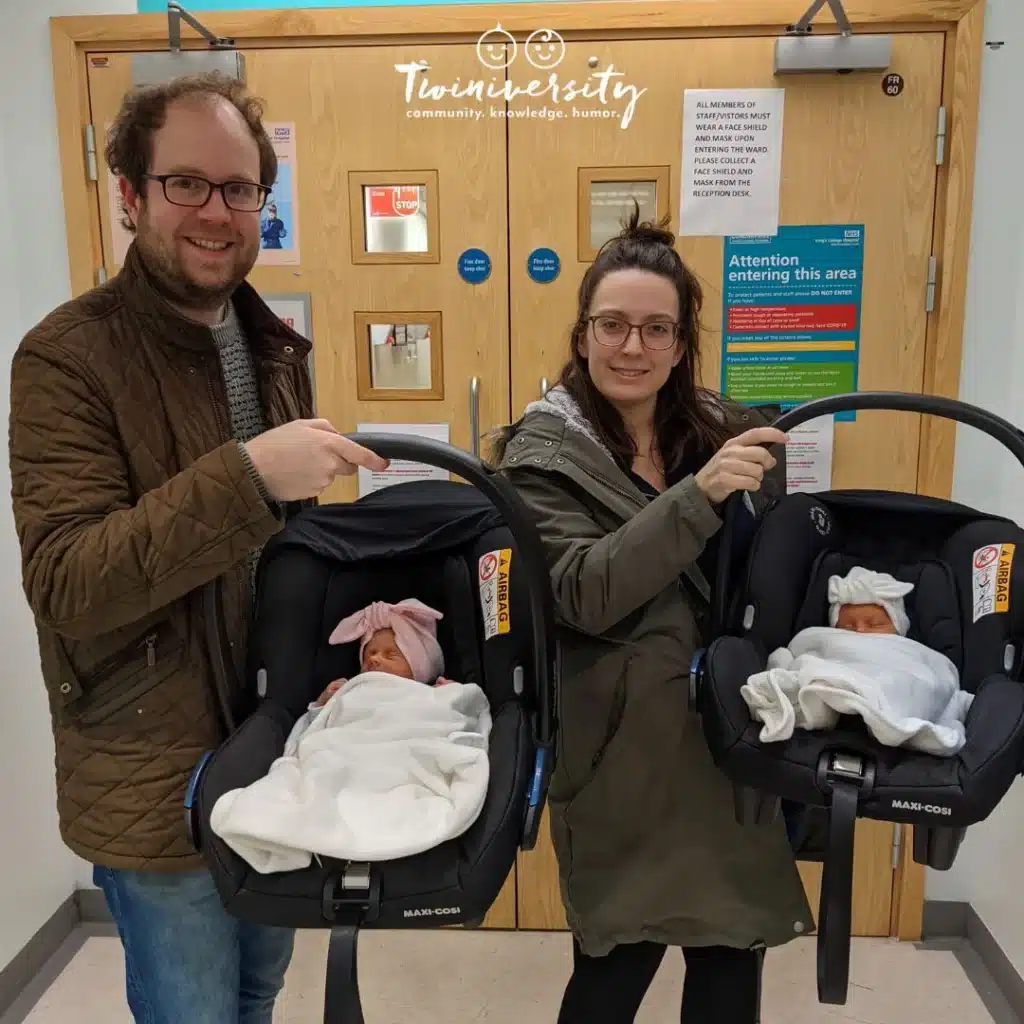 Twin parents holding their newborn babies in their infant car seats